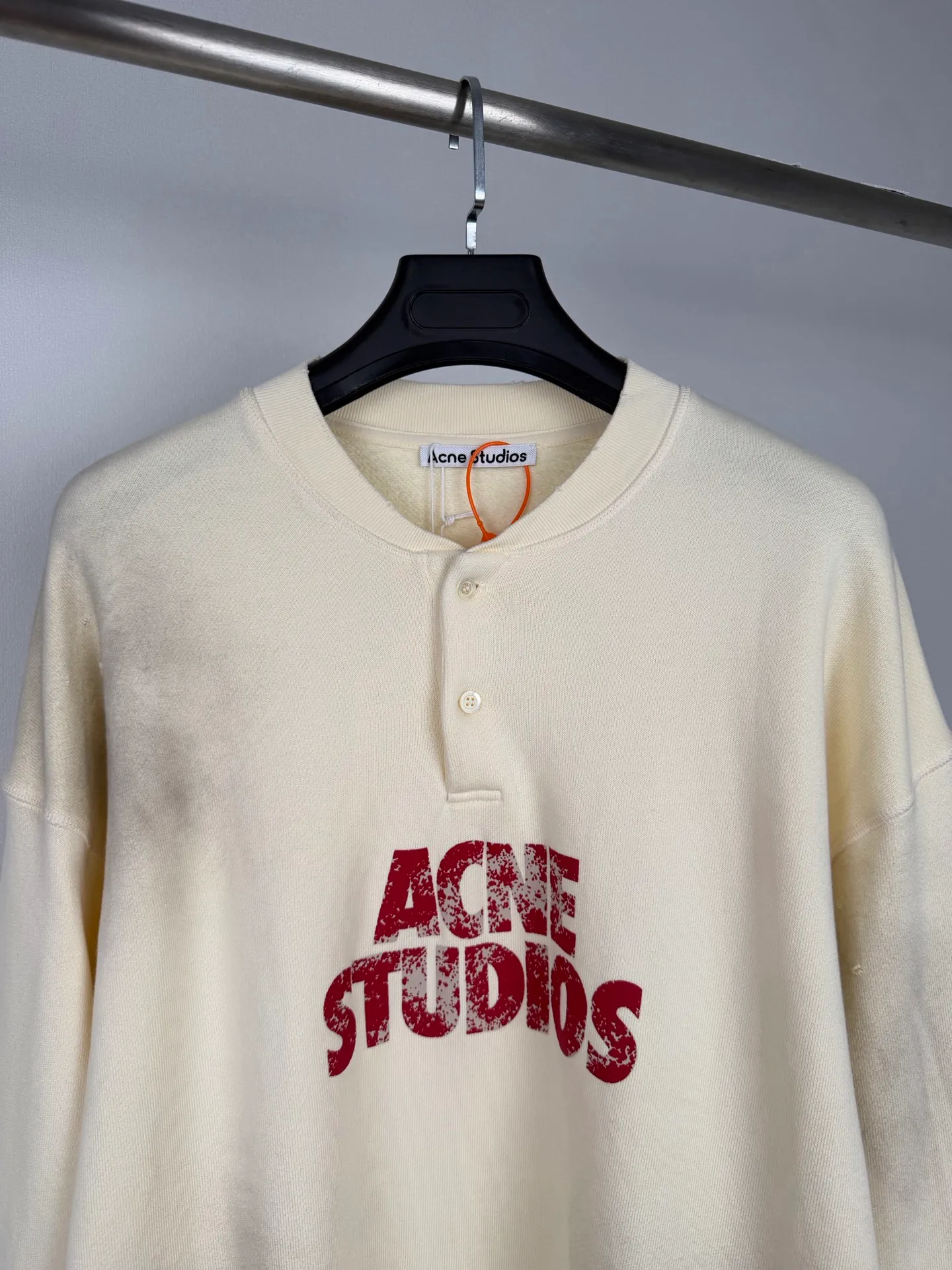 Acne Studios logo-printed distressed sweatshirt, custom-made fleece-soled sweatshirt, thick and soft, warm to the touch, Cream White ready-to-wear, warm matte texture spread across the fabric, slowly spreading the unique Scandinavian cool and luxurious charm, Henry collar half-button placket outlines the soft collar line, elegantly modifies the neck contour, mottled red brand letter print engraved on the body, Retro worn texture contains narrative heritage Ribbing tightly locks the cuffs and hem, firmly shaping the body, loose and relaxed shoulder silhouette, eliminating redundant decorations. The collision between the soft background color and retro printing interprets the minimalist, relaxed and elegant style of Acne Studios. Process 1: Use an imported fully automatic flat screen printing machine to print the special printing slurry containing microcapsule foam particles on the surface of the fabric. After being heated in a high-temperature drying tunnel, the microcapsules in the slurry expand and swell when cooled and set. Process 2: Gradient distressed spray process. By spraying dyes of different colors on the surface of the fabric, the clothes can show rich color changes under different lights and increase the visual layering. Process 3: Positioned manual fraying. Local friction and wear on the fabric through manual operations. The surface of the fabric will form a natural damage effect. It is time-consuming and labor-intensive. The daily output is low. Process 4: The fabrics have been fermented and washed. The hand feel and texture are better. It is not easy to deform, not easy to shrink, not easy to fade, and maintains long-term beauty. Accessories: Customized 1:1 Acne buttons Customized 1:1 Acne trademark Version: Loose version Size: S M L XL